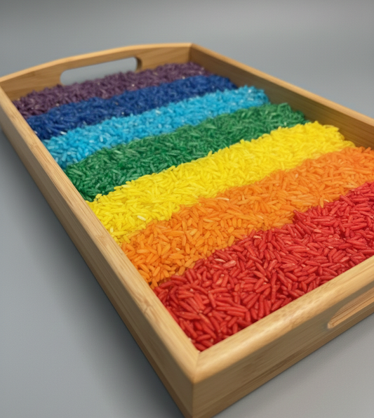 Wooden tray with rainbow-colored rice on a gray background