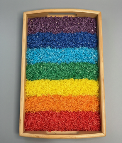 Colorful layered rainbow rice in a wooden tray on a gray background