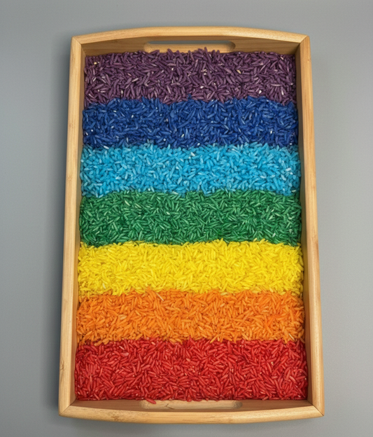 Colorful layered rainbow rice in a wooden tray on a gray background